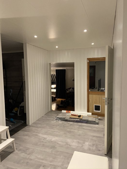 Nyinstallerat grått vinylklickgolv i ett hem under renovering, med verktyg och byggmaterial synligt.