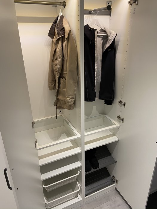 Öppen vit garderob med hyllor och klädstång med kläder och skor, designad för att se inbyggd ut.