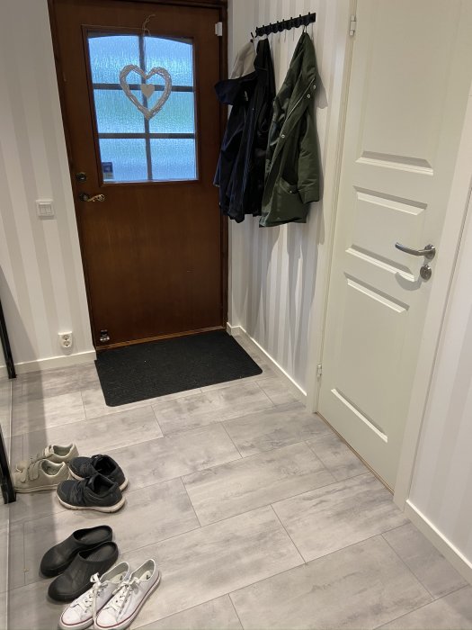 Entré med installerade golvlist och dörrfoder, ytterdörr och klädhängare.