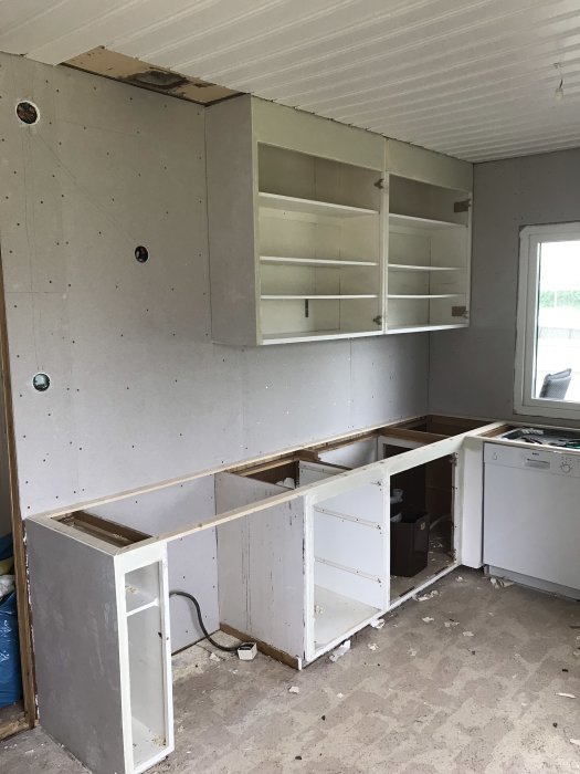 Köksrenovering med nymålade och spacklade skåpstommar och vägg redo för kakelsättning.