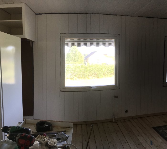 Inomhusvy av ett rum med nyinstallerad vit stående Moelven-panel på väggarna och synligt byggmaterial.