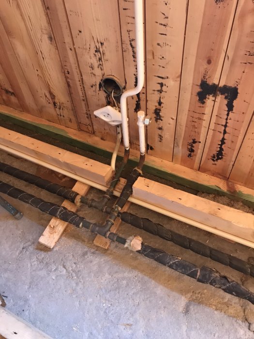 Nyligen installerad elinstallation och rör vid en trävägg, redo för isolering.