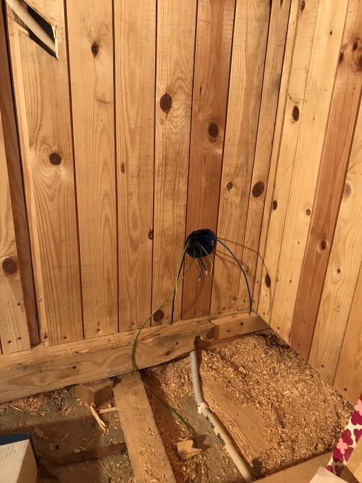 Elektriska ledningar dragna genom en trävägg väntar på isolering i ett byggprojekt.