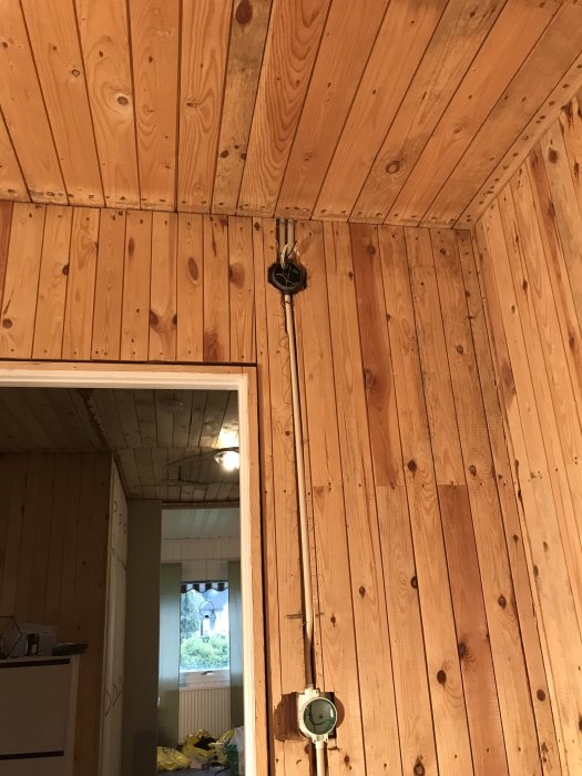 Elektriska installationer i ett träpanelt rum med synliga kablar och uttag före isolering.