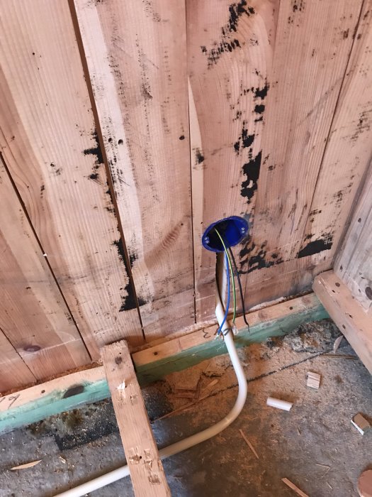 Eluttag med färdigdragna kablar på en trävägg, förberett för isolering.