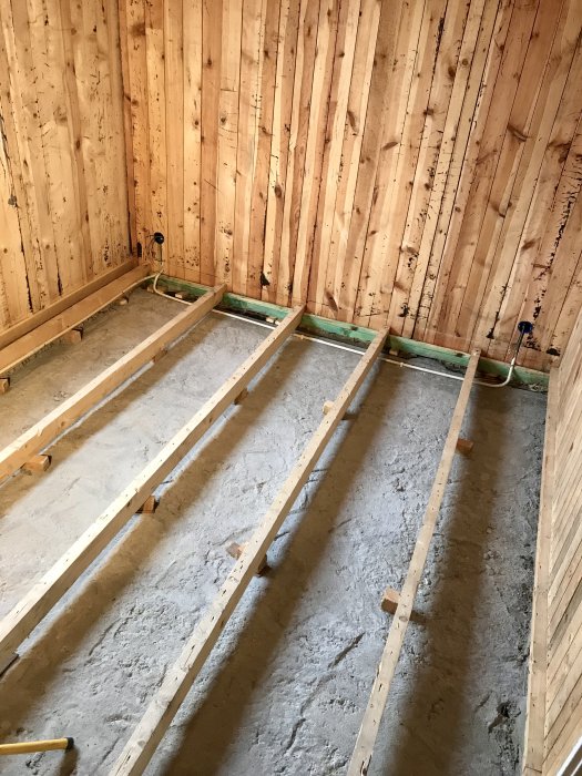 Interiörbyggnadsstomme med träväggar och utdragna elkablar, redo för isoleringsarbeten.