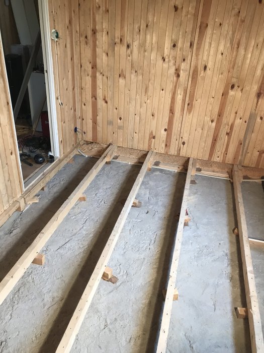 Färdigdragen elektricitet i ett rum under renovering med träreglar på betonggolv inför isoleringsarbete.