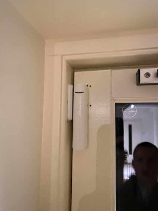 Doorprotect plus monterad på dörrkarm med öppen dörr i bakgrunden.