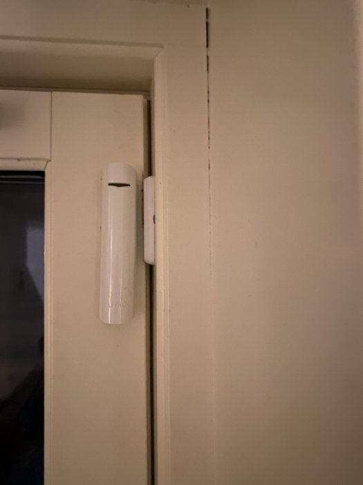 Montering av Doorprotect Plus dörrsensor på karmen av en vit dörr.