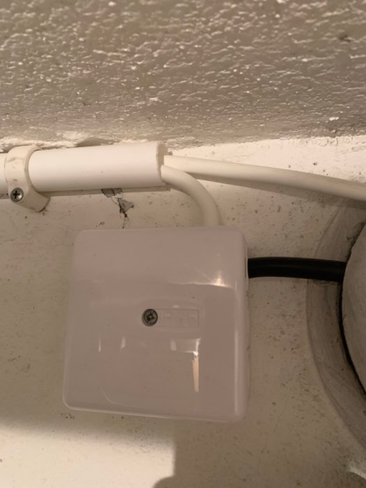 Elkablar dragna genom ett ventilationsintag mot en vägg med en ansluten eldos.