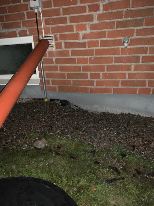 Elkablar som dragits in genom ventilationsintaget på en tegelväggs exteriör.