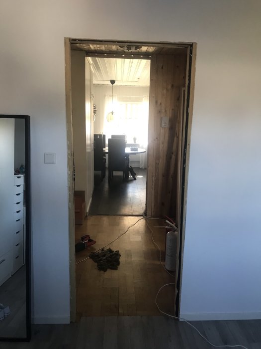 Renoveringsarbete i hemmiljö med nytt trägolv, dörröppning utan dörr och byggmaterial på golvet.