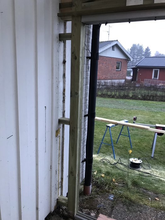 Hörn av hus under renovering med oskyddad regel och isolering, vidarbetningsförslag "klä in det med panel".
