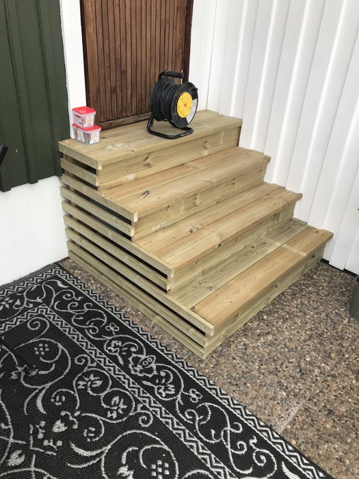 Nybyggd trätrappa ut mot uterum med kablarulle och färgburkar på toppsteget.