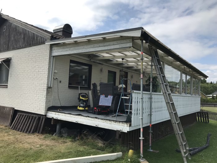 Ställningsmaterial används som stöttor för ett hus med en inglasad veranda i behov av renovering.