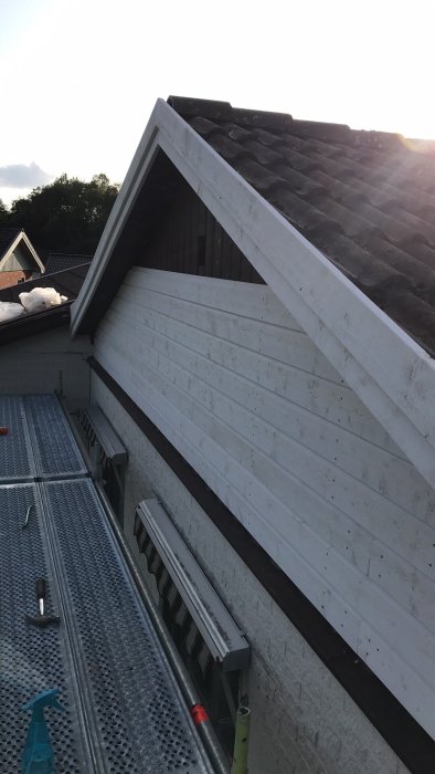 Renovering av husgavel med ny liggande vit panel under skymning.