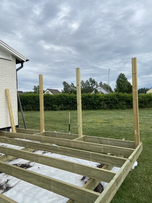 Nybyggd trätrall utan räcken med stolpar redo för räckesmontering vid ett hus.