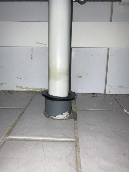 Installation av gumminippel som förbinder ett 40mm avloppsrör med ett 50mm golvutlopp i ett badrum.