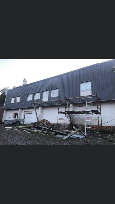 Renoverat hus med oavslutad balkong och byggmaterial på marken.