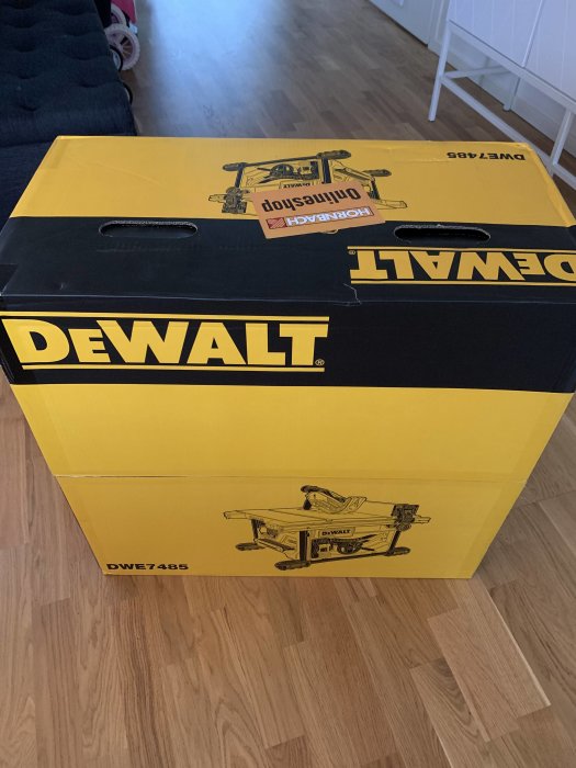 Oöppnad gul och svart Dewalt DWE7485 sågbordsförpackning på ett golv.