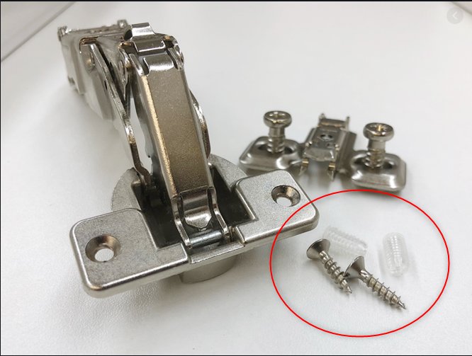 Skåpgångjärn med tillhörande skruvar och genomskinliga skruvpluggar på ett vitt bord.