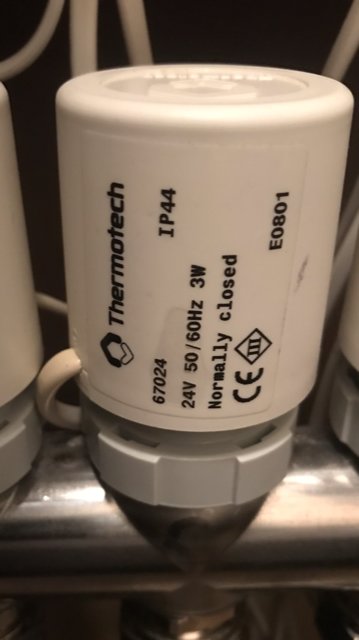 Ställdon från Thermotech markerat "Normally Closed" monterat på rörledning.