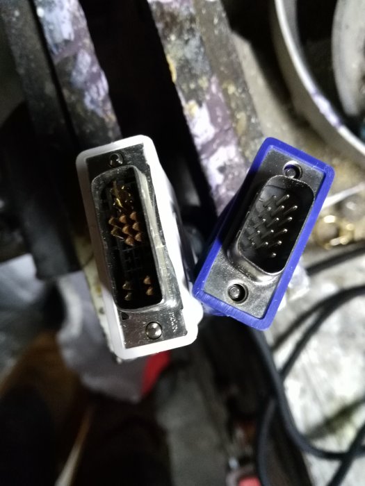 En DVI-kabel med vit kontakt och en VGA-kabel med blå kontakt mot en suddig bakgrund.