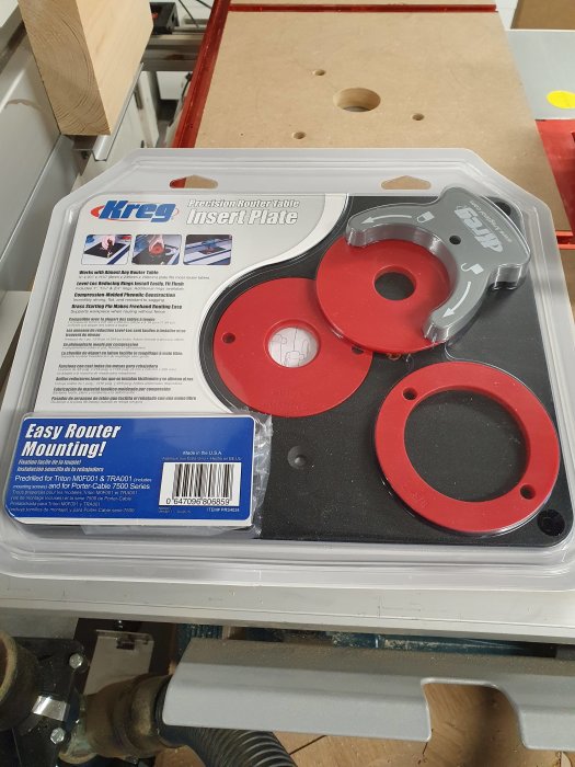 Färdigpackad Kreg Precision Router Table Insert Plate med guider och ringar på en verkstadsbänk.