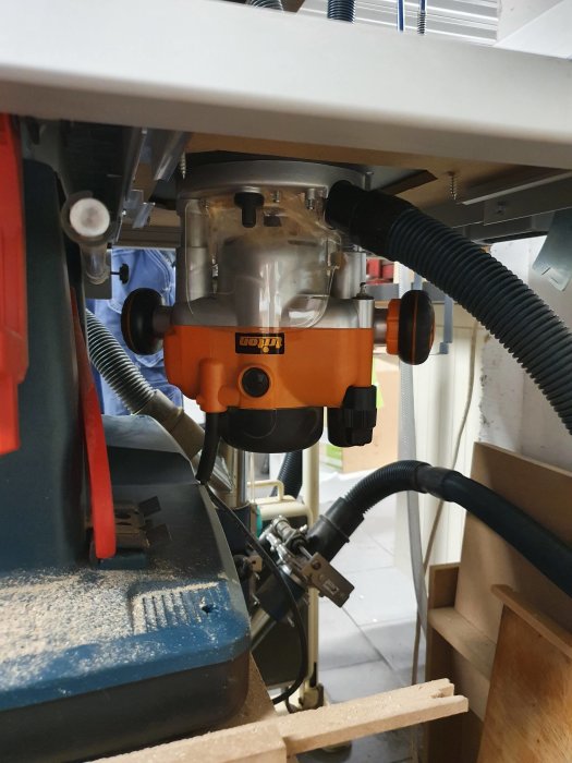 En monterad fräs i arbetsmiljö med sladdar och dammsugarslangar.