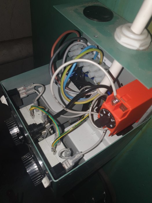 Öppet elpatronskåp med termostater, ledningar och säkring för uppvärmningssystem hemma.