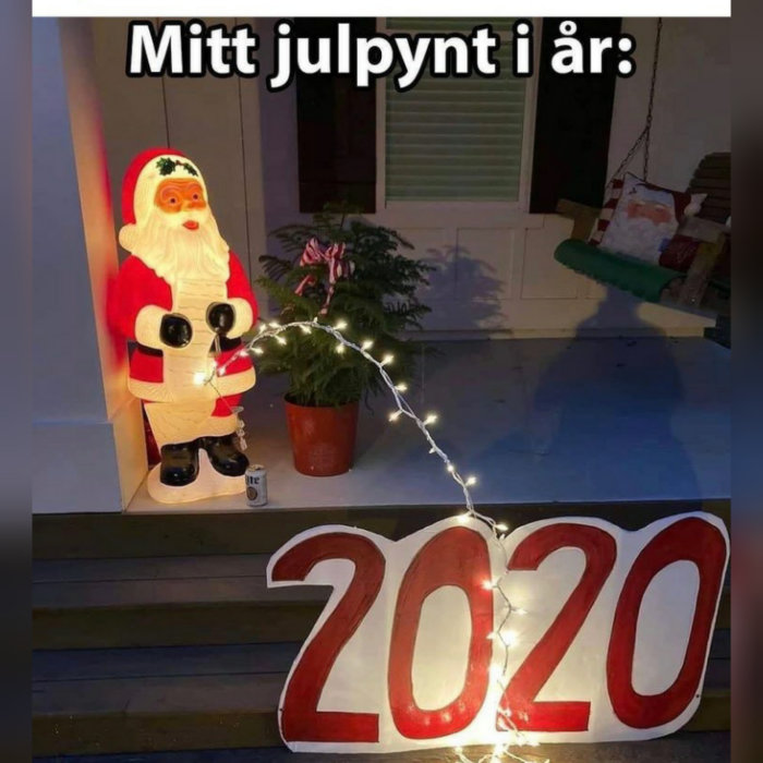 Juldekoration med upplyst tomtfigur som håller i en ljusslinga, med siffrorna "2020" nedanför och gungstol i bakgrunden.