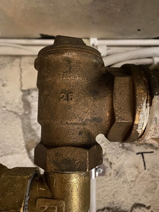 T-koppling av metallrör med en siffra 25, eventuellt pluggad, i en VVS-installation.