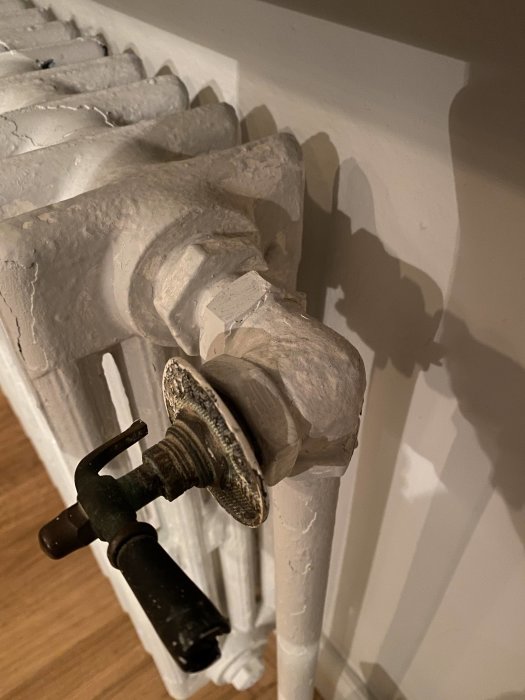 Gammal termostatventil på radiator med tydliga tecken på läckage och behov av underhåll.