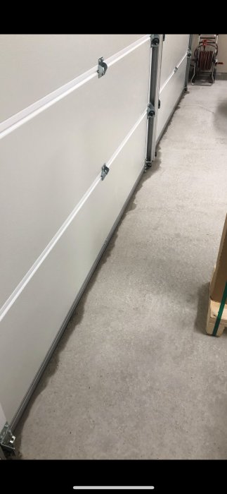 Nybyggt garage med stängd port och fukt på betonggolvet nära portarna.