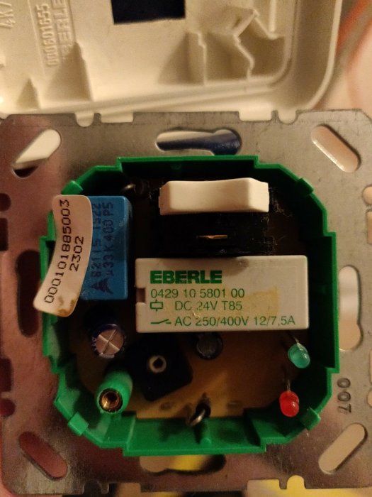 Gammal Eberle termostat synlig vid en väggmonteringsyta, med elektroniska komponenter och ledningar.