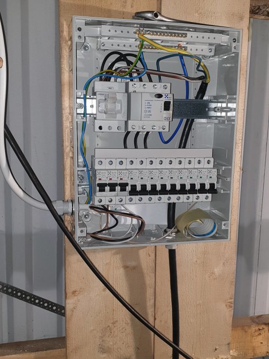 Öppen elcentral med dragna ledningar och automatsäkringar för svarv och svets, ej helt klamrade.