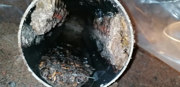 En igensatt avloppsrör med fett och rester som orsakar avrinningsproblem i ett kök.