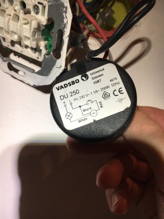 Hand håller en VADSBO universell dosdimmer med wiring instruktioner för svart, vit och röd kabel.