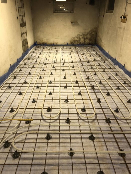 Färdigställt golv med armeringsnät och installerade provtryckningsslangar för betonggjutning.
