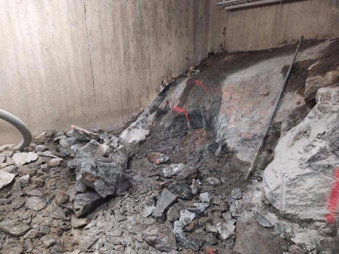 En stor stenblock med sprickor och redskap fastnat i blocket på en byggarbetsplats.