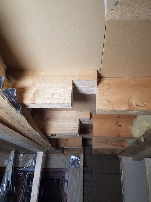 Wooden beams and joists in a construction project, showcasing modifications with different sizes and setups, including a cut 45x105 piece.