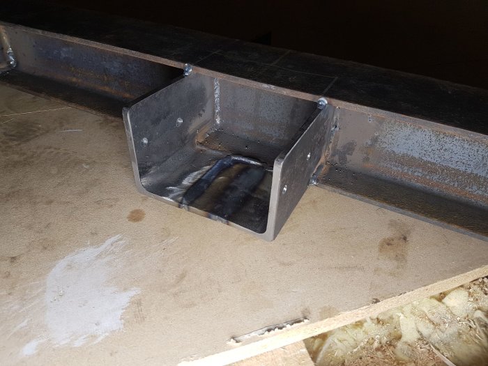 Metal beam connection with a welded bracket on wooden surface, showing construction modifications discussed for building support.
