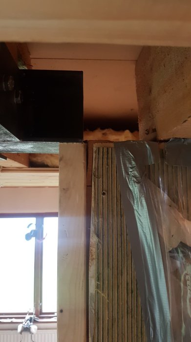 A modified wooden beam structure with duct tape and insulation, illustrating home renovation with a focus on construction adjustments and stability.