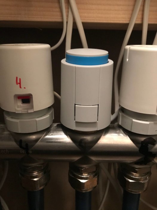 Värmeregulatorer på rör med en blå toppdel halvt utskjuten indikerande öppet läge.
