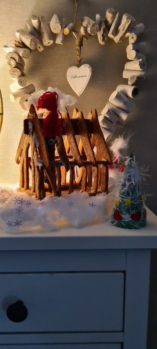 En hemmagjord pepparkaksstomme som liknar en byggnadsstomme, med en julgran och "Välkommen"-skylt.