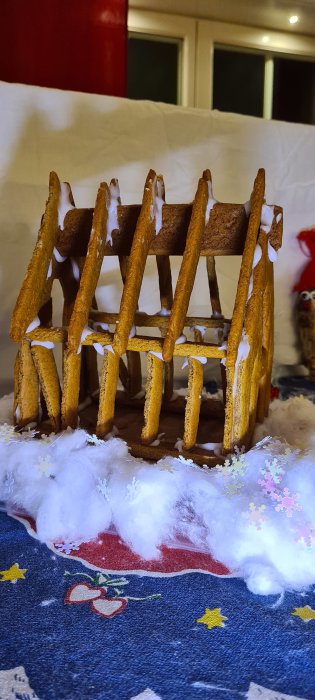 Pepparkaksstomme med vita glasyrskarvar på julduk med snölik bomull och snöflingeformar.