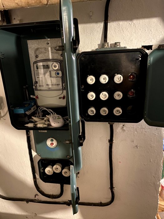 Gammal elektrisk fördelningscentral i källare med mätare och säkringar.