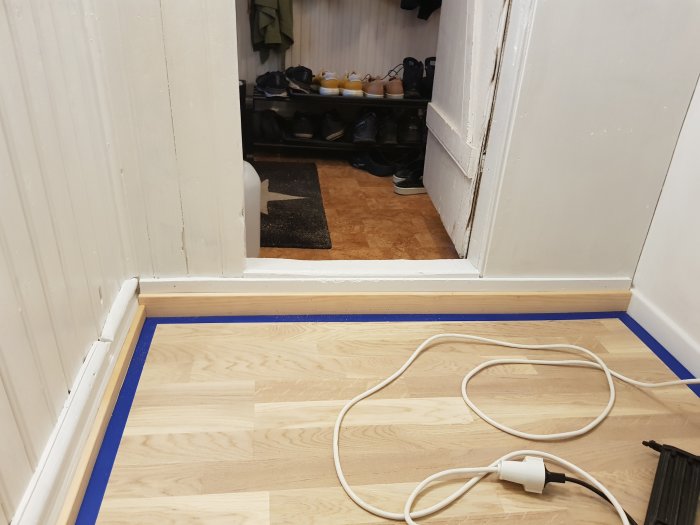 Nyinstallerat laminatgolv och lister i ett utrymme under en trappa.