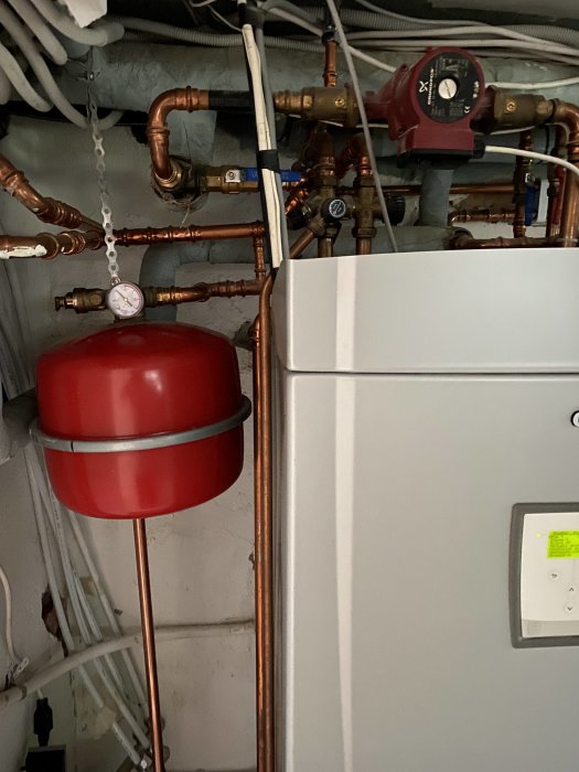 Installation i ett pannrum med kopparledningar, expansionskärl och en cirkulationspump.