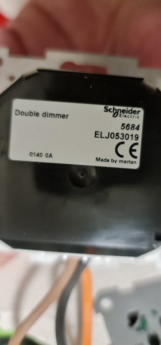 Närbild av en Schneider Electric dubbel dimmer 5684, visar märkning och modellnummer på en svart bakgrund.